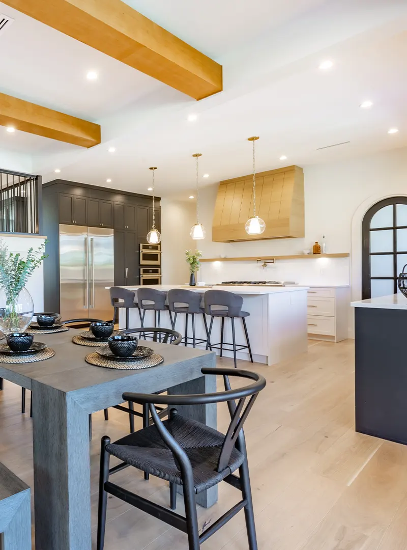Automated Kitchen Lighting Scene With The Right Amount Of Incoming Natural Light. The Dining Table And Chairs Are In Dark Tones That Contrast With The Light And Warm Tones Of The Walls And Ceiling, Creating A Balanced And Modern Atmosphere.